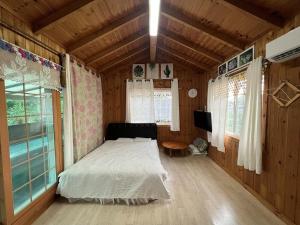 a bedroom with a bed in a wooden house at Jeju neulpureon house in Jeju
