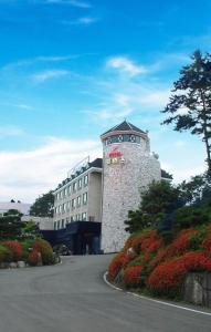 a building with a tower with flowers in front of it at Prince Hotel in Goseong +2 photos