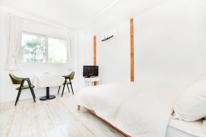 a white bedroom with a bed and a table at Sweet Pension Yangyang in Yangyang