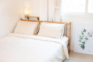 襄阳郡Sweet Pension Yangyang的卧室里有一张床，床单和枕头都是白色的