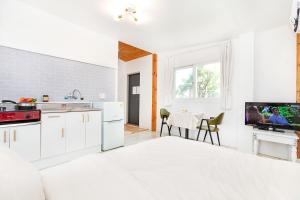a kitchen with white cabinets and a table with a tv at Sweet Pension Yangyang in Yangyang +22 photos