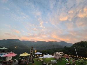 a group of tables and umbrellas in a field with mountains at Yangju Gray Castle Pension in Yangju