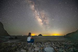 a woman standing on a beach under a starry sky at Jeonnam Cheongsando Yeohaeng Pension in Wando