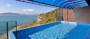 a large swimming pool with a view of the ocean at namhae ingaelreoripulbilra in Namhae