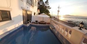 a swimming pool next to a building with a view of the ocean at Yeosu Sound of Music Pension in Yeosu
