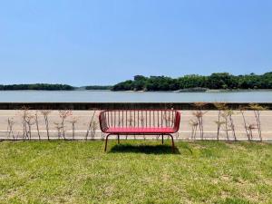a red bench sitting in the grass near a body of water at Daeboodo Prince Pension in Ansan +11 photos