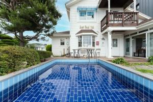 a blue tile swimming pool in front of a house at Daeboodo Prince Pension in Ansan