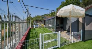 a white fence with an umbrella in a yard at Daeboodo Podohyangki Pension in Ansan