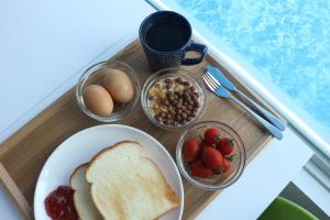 a tray with a plate of bread and bowls of fruit at Incheon donggeumdo hanguk villa in Incheon