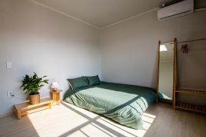 a bedroom with a green bed in a white room at Yangyang Stay in Bricks in Yangyang
