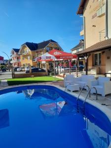 a swimming pool with chairs and an umbrella at Pensiunea ALAS in Baile Felix