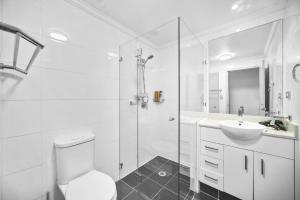 a white bathroom with a toilet and a sink at Cozy 2Beds APT with Pool Access in Waterloo in Sydney +9 photos