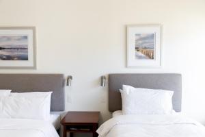 two beds in a hotel room with paintings on the wall at Pastoral Hotel Motel in Port Augusta