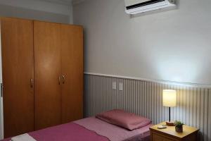 a bedroom with a pink bed and a cabinet at Apartamento Confortável em Guaratinguetá in Guaratinguetá +16 photos