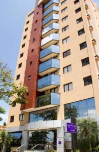 a tall building with a purple sign in front of it at Apartamento Confortável em Guaratinguetá in Guaratinguetá