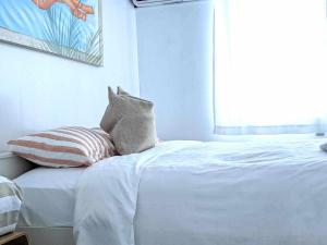 a white bed with two pillows and a window at The Surf Lodge White Beach in Shimoda +12 photos
