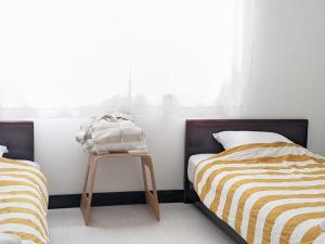 a bedroom with two beds and a table with a bag on it at The Surf Lodge White Beach in Shimoda