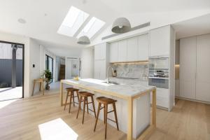 a kitchen with white cabinets and a island with bar stools at Villa Aquarius - Gas Heated Pool Spa Luxury in Blairgowrie