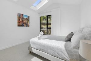 a white bedroom with a bed and a window at Villa Aquarius - Gas Heated Pool Spa Luxury in Blairgowrie +13 photos