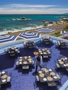 a man standing on a patio with tables and chairs at Twelve Apostles Hotel & Spa in Cape Town