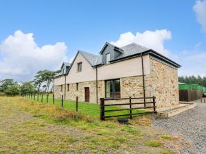 a stone house with a fence in front of it at The Barn, Drumbow Farm in Airdrie