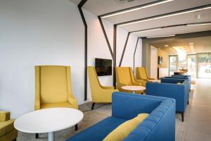 una sala de espera con mesas y sillas azules y amarillas en Hotel Yacht Wellness & Business, en Siófok