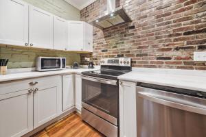 una cocina con armarios blancos y una pared de ladrillo en Urban Oasis Haven in St Catherine, en Louisville 38 fotos más