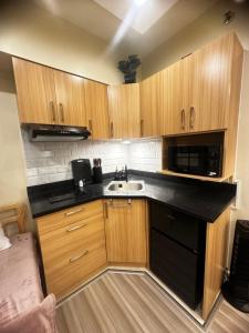 eine kleine Küche mit Holzschränken und einer Spüle in der Unterkunft Avida Riala It Park Fast wifi in Cebu City