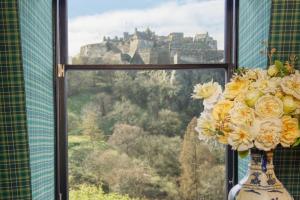 a vase filled with flowers in a window with a castle at 100 Princes Street in Edinburgh +64 photos