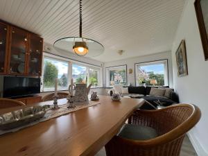 ein Wohnzimmer mit einem Holztisch und einigen Fenstern in der Unterkunft Zur Himmelsleiter in Westerland