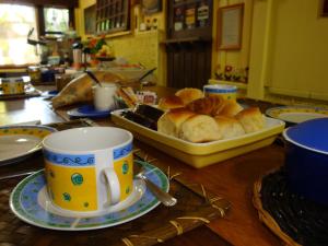 a table with cups and a tray of bread at Pousada Enseada das Conchas in Ilha do Mel