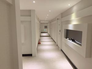 a long hallway with white walls and a television at Yun's hotel in Tongyeong