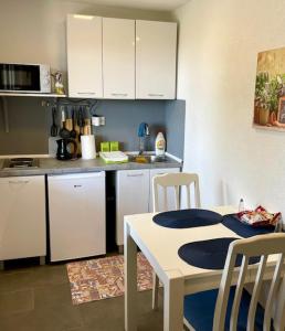 eine Küche mit weißen Schränken und einem Tisch und Stühlen in der Unterkunft Sutomore Panorama Apartment in Sutomore + 14 Fotos