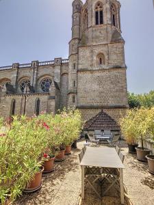 Un edificio con una torre de reloj con una mesa y plantas en macetas. en Apartment La Terasse, en Carcassonne
