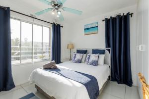 ein Schlafzimmer mit einem Bett mit blauen Vorhängen und einem Fenster in der Unterkunft Laguna La Crete 12 in Uvongo Beach + 18 Fotos