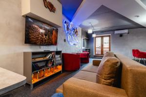a living room with a couch and a flat screen tv at AYKUN Capsule Hotel in Almaty