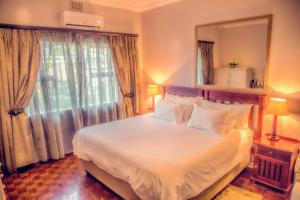 een slaapkamer met een groot bed met een groot raam bij Nauntons Guest House & Wedding Venue in Ladysmith