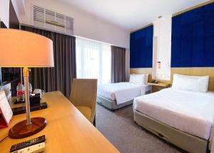 a hotel room with two beds and a desk at Swiss-Belinn Malang in Malang