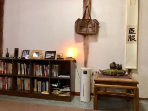 丽江Jayden NAXI Healing Lodge臣安纳西疗愈小院 - Namaste的书架和台灯桌子的房间