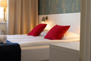 a bed with two red pillows on top of it at SeaSide Sopot - butikowe noclegi przy plaży in Sopot