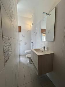 Un baño con lavabo, inodoro y espejo. en La Casa di Modica, en Módica