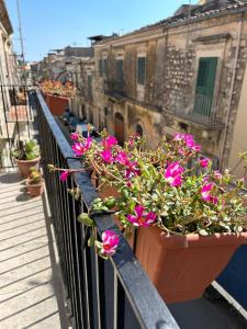 una fila de flores en macetas en un balcón en La Casa di Modica, en Módica