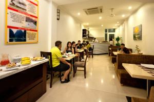 a group of people sitting at tables in a restaurant at Rising Dragon Hotel in Hanoi