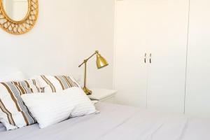 a white bedroom with a bed with a lamp and a mirror at Precioso piso en el centro de la ciudad con vistas in Santa Cruz de Tenerife