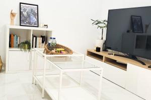 a white living room with a tv and a glass table at Precioso piso en el centro de la ciudad con vistas in Santa Cruz de Tenerife