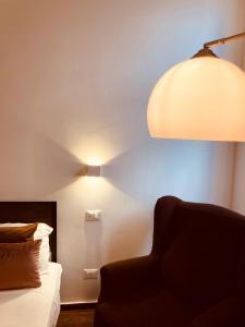 a room with a bed with a lamp and a chair at Domus Mylae in Milazzo +7 photos