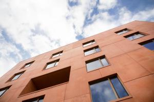 a tall orange building with the sky in the background at Hostel Groeninghe in Kortrijk