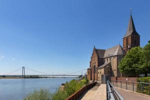 a church with a tower and a bridge in the background at Ferienwohnung Rheinpark Emmerich Rheinblick, Balkon & Parkplatz in Emmerich