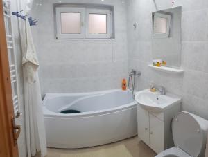a bathroom with a tub and a toilet and a sink at City Apartment in Târgu Ocna