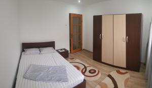a bedroom with a bed and a cabinet and a rug at City Apartment in Târgu Ocna